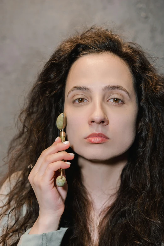 a woman with dark hair is holding a cellphone to her ear