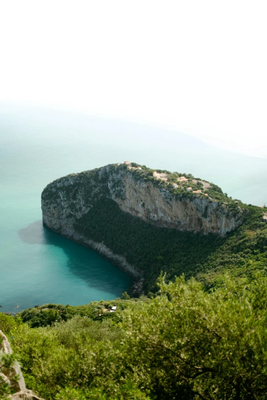 a view from the top of a hill looking at a rock island and body of water