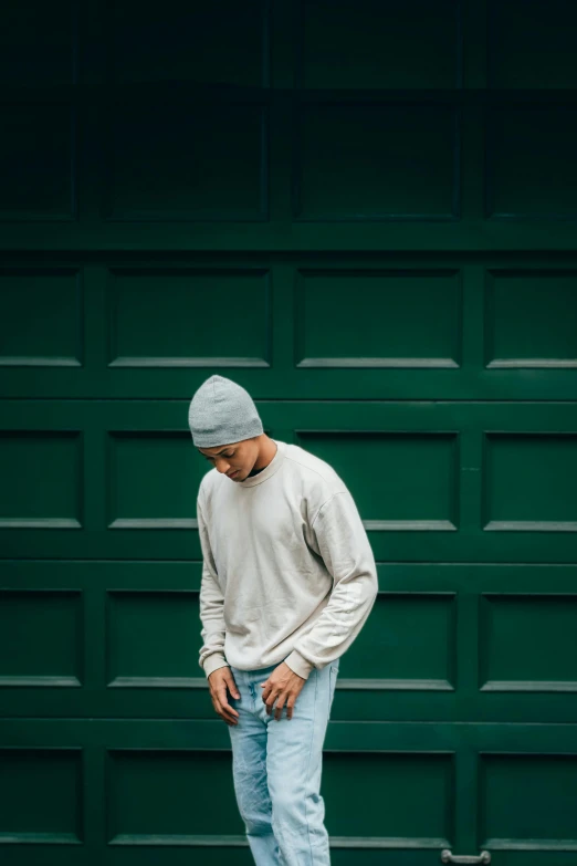 a guy in white shirt and cap standing next to garage door