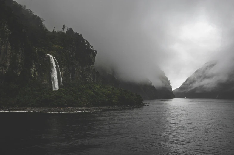 a black and white po of a waterfall with trees and water