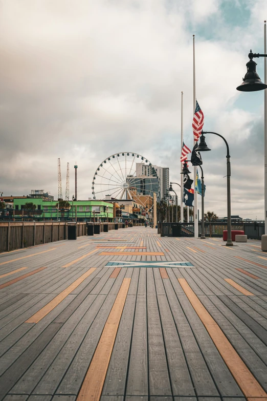 there is a boardwalk in a city with buildings and a ferris wheel