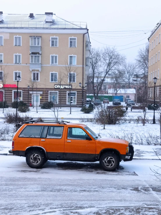 an orange truck is parked in the snow near buildings