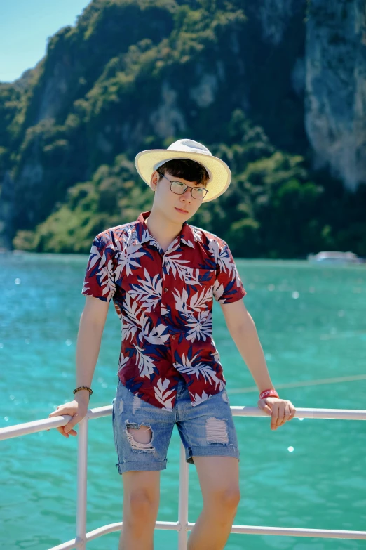 a boy in a hat and blue shorts stands on a boat