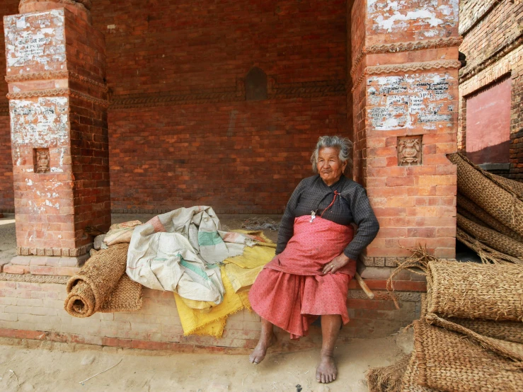woman sitting in doorway with pile of goods outside