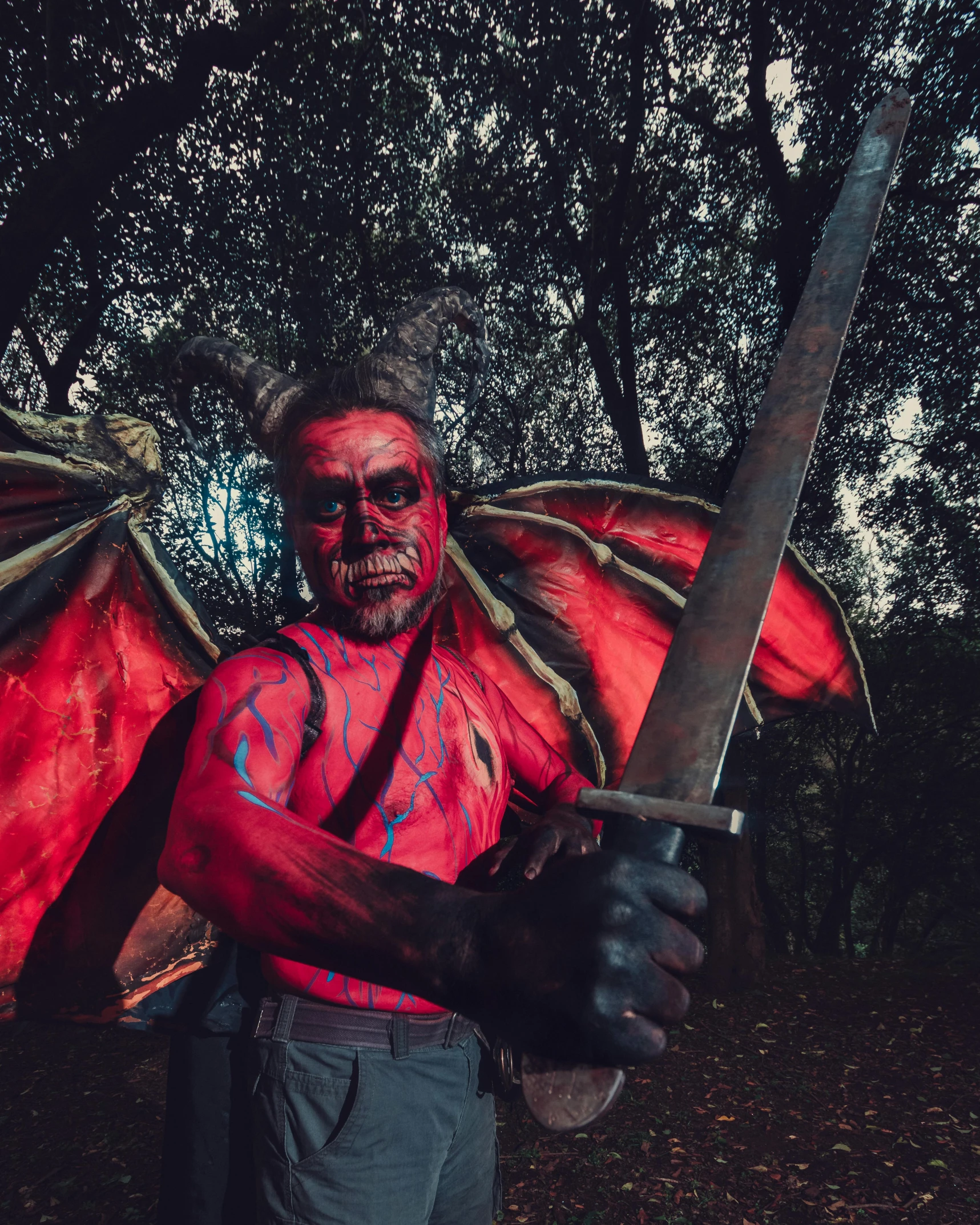 man wearing halloween makeup and wings carrying sword