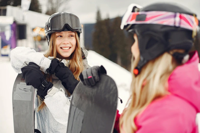 a woman standing next to another woman holding a snowboard