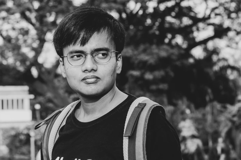 a young man in glasses standing with a backpack