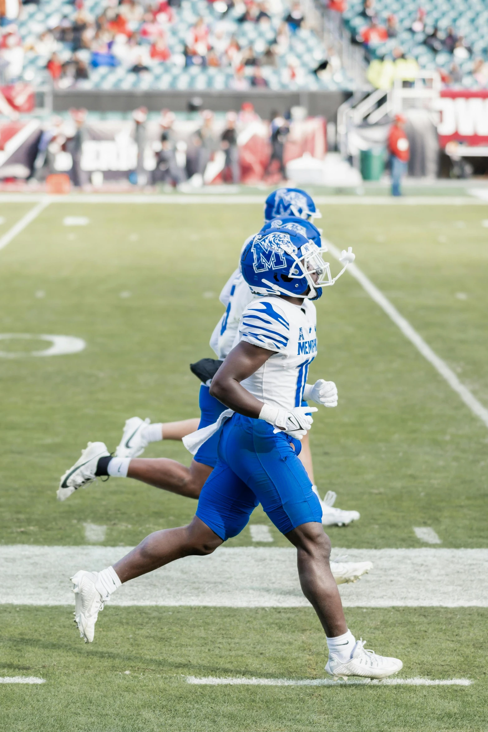 two men running down a football field in the process of playing football