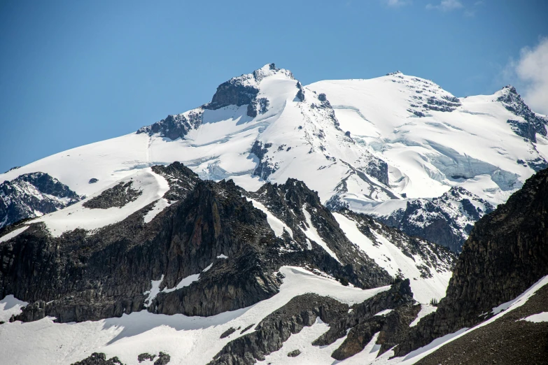 an aerial view of snow covered mountains against a clear blue sky