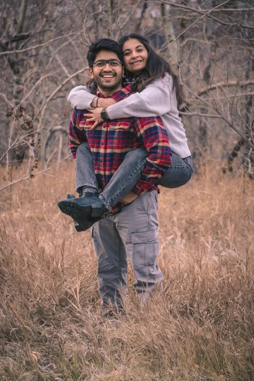 a man and woman standing in the middle of a field hugging