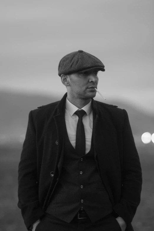 a man in a suit and hat smoking a cigarette