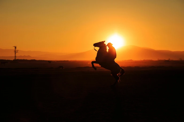 there is a horse that is riding at sunset