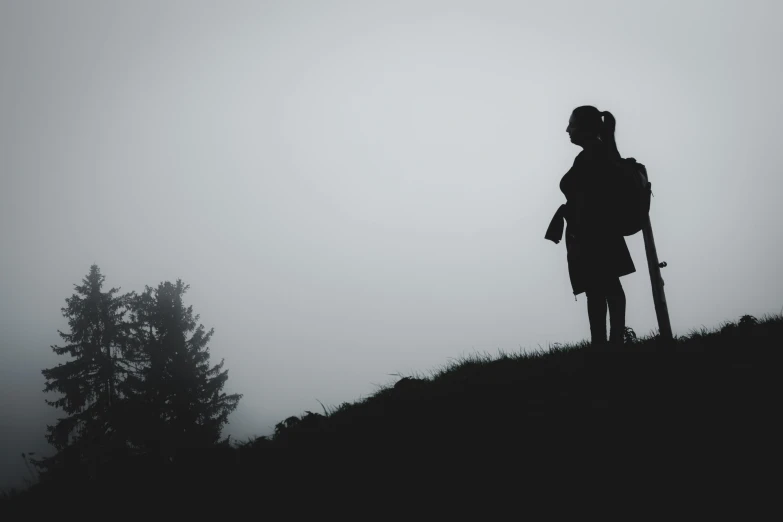 the silhouette of a female hiker overlooking a misty mountain