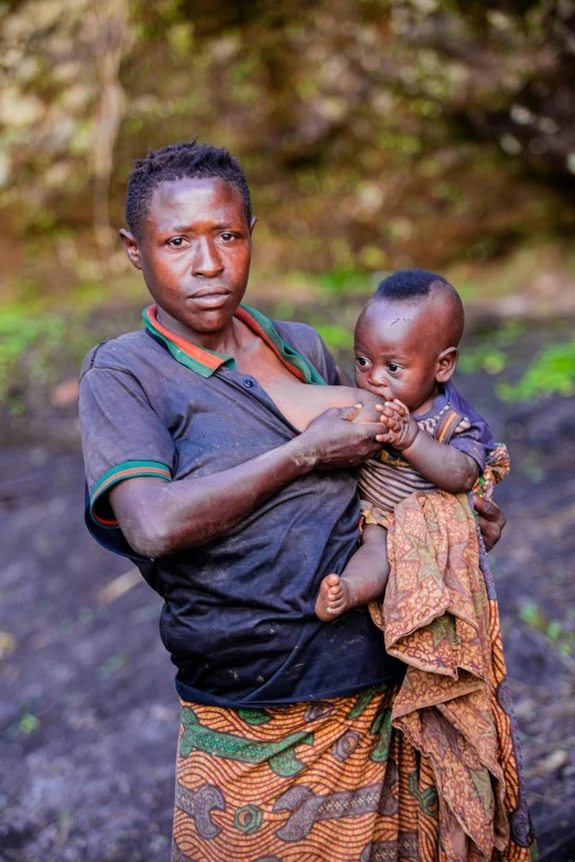 a woman is carrying her child across the dirt