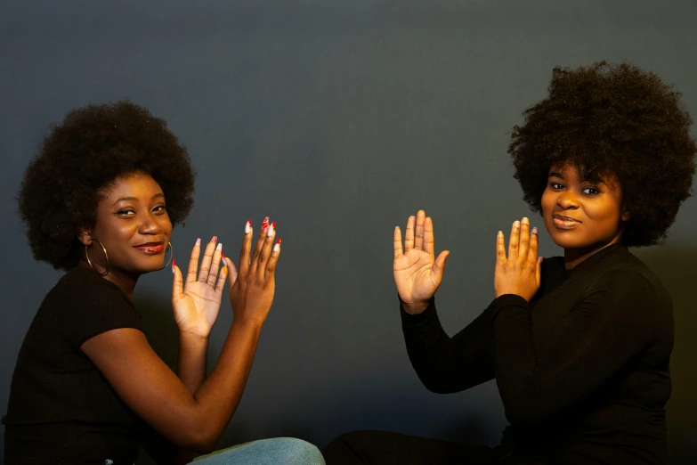 two women sitting down and making hand gestures