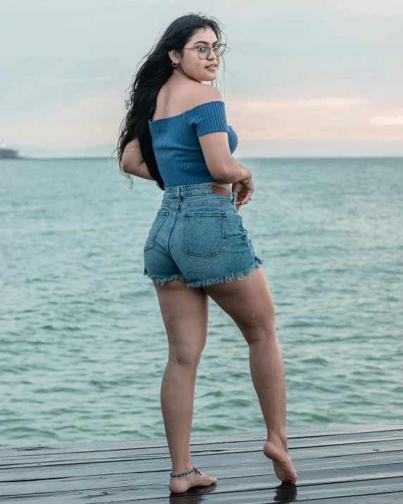 a woman with large  wearing denim shorts by the water