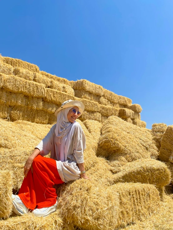 woman sitting on straw bales with clear blue sky in the background