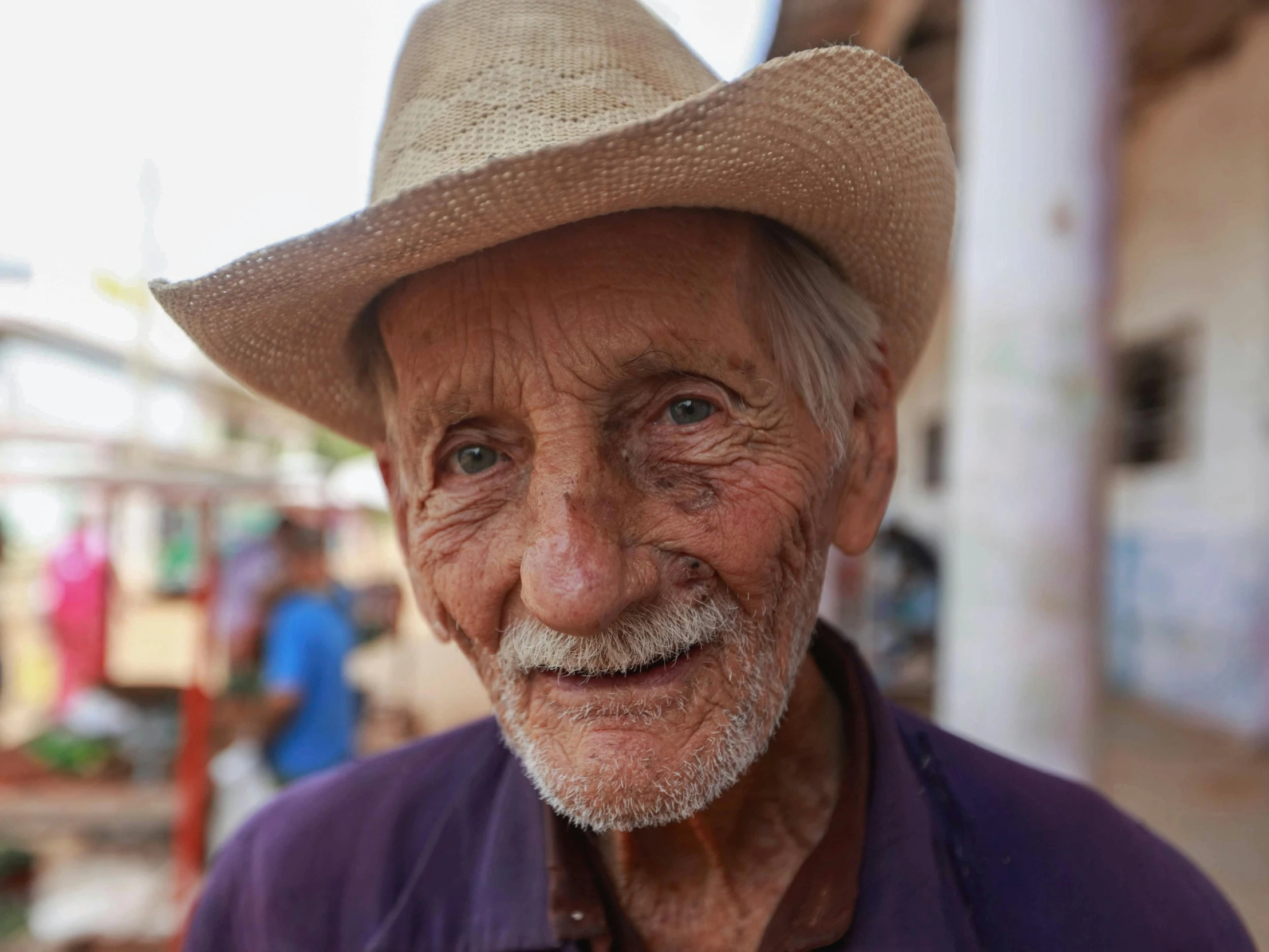 the old man is wearing a hat while walking