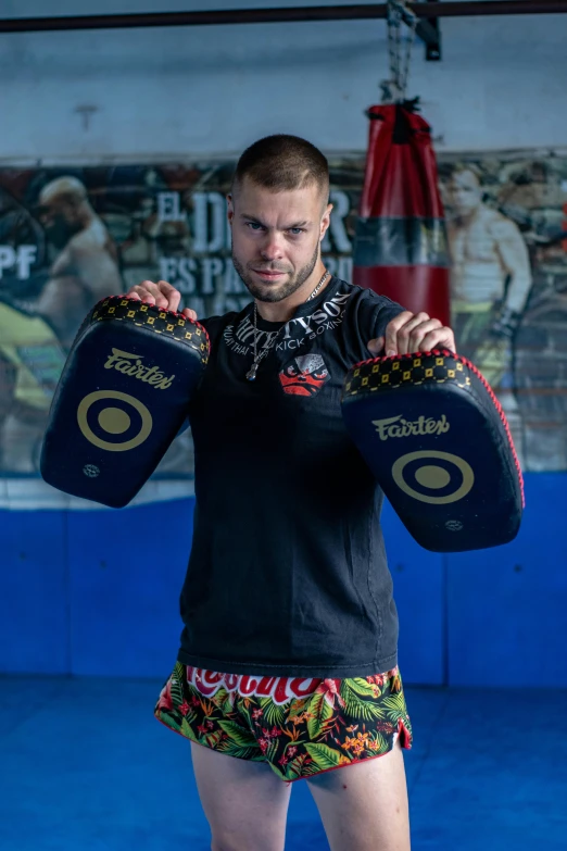 a man standing holding a boxing bag while wearing shorts