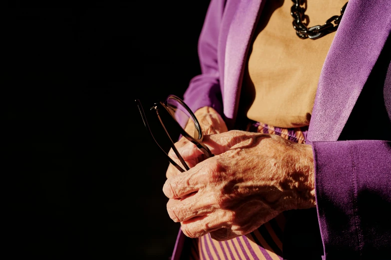an older woman holds her glasses in her hand