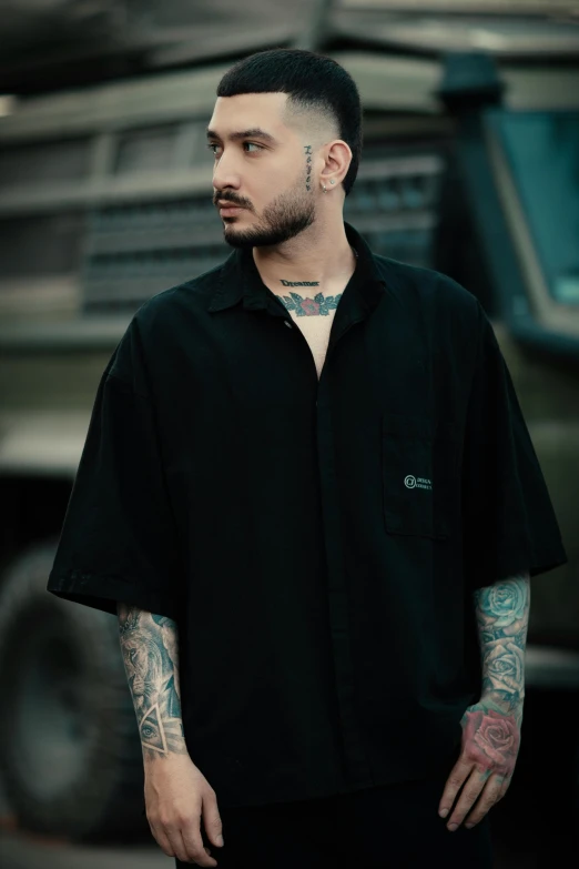 a man with tattoos and piercings standing in front of a car