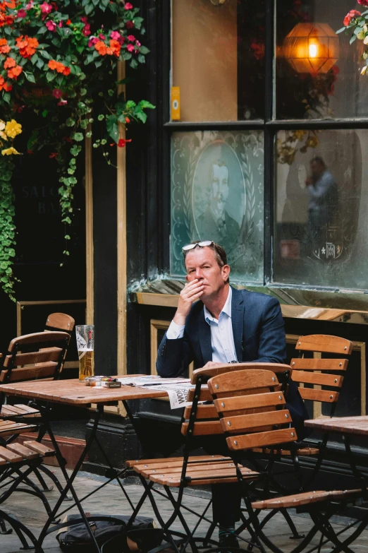 a man sitting at an outdoor table in front of a building