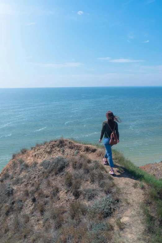 a young woman standing on the top of a hill overlooking the ocean