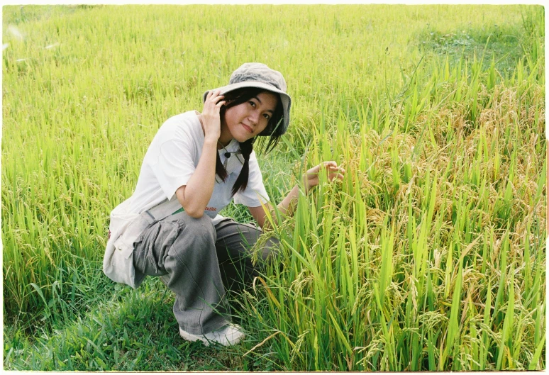 a person kneeling down in a grassy field with a cellphone