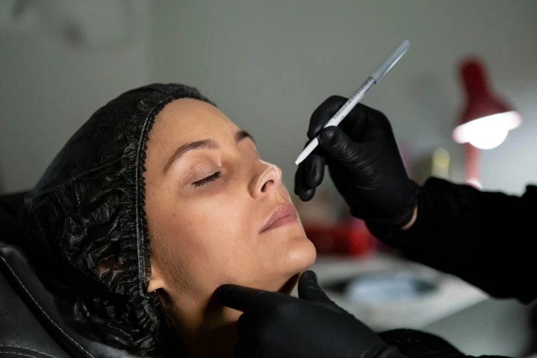 a woman getting her eyebrows trimmed while sitting in a barber shop