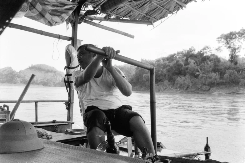 a boy is sitting on a boat and using a large instrument