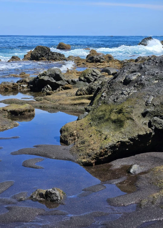 waves splash against the rocks as they wash on the beach