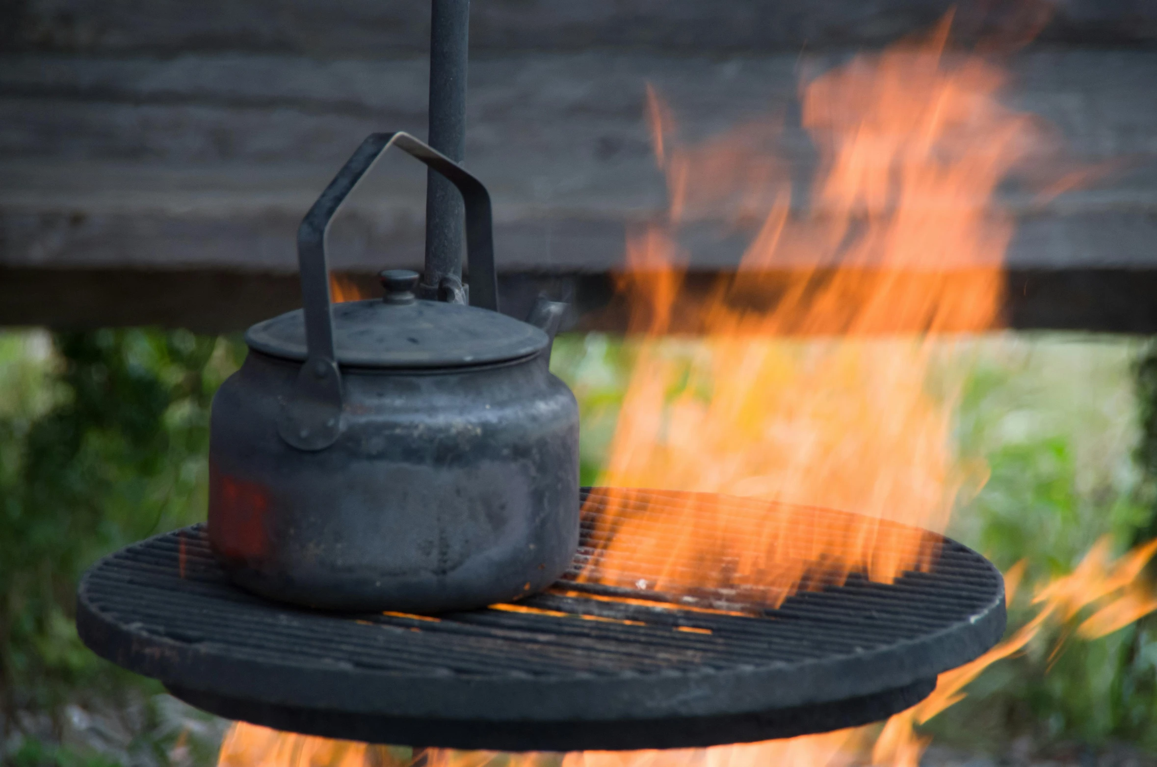 a kettle on a grill with flames in the back yard