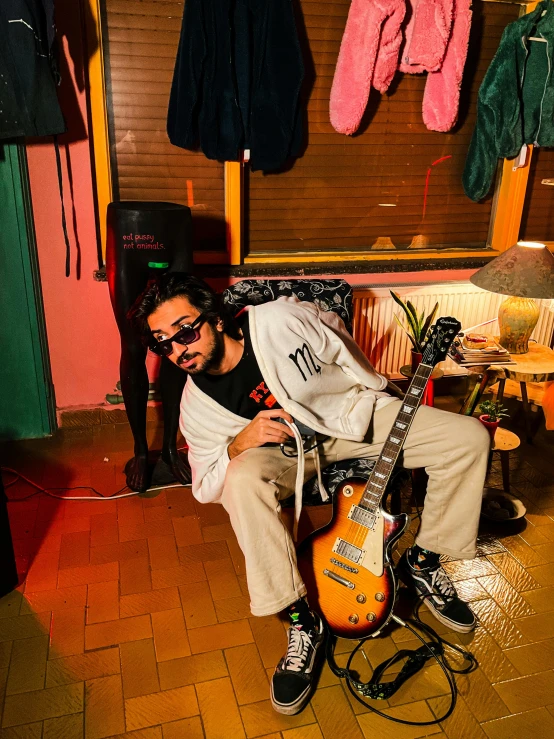 a man holding up an electric guitar sitting on the floor