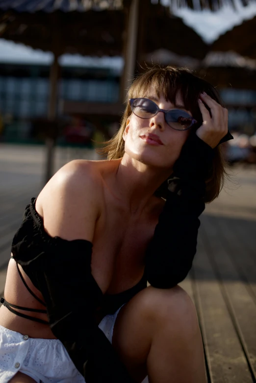 a woman sitting on a wooden plank while wearing sun glasses