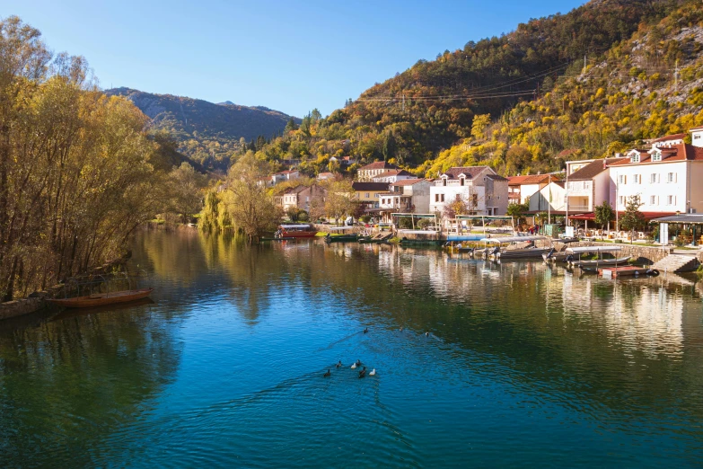 a river with lots of small buildings next to a hillside