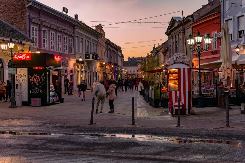 a crowd of people walking down a sidewalk next to shops