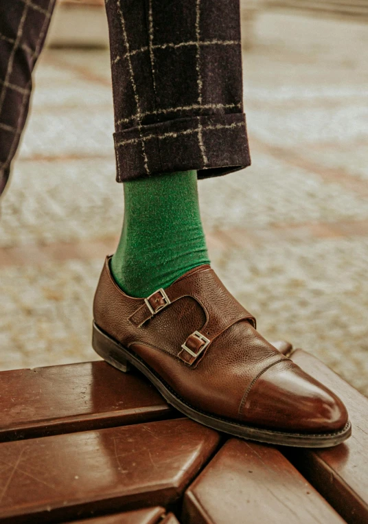 a man with green socks and boots standing on some brick