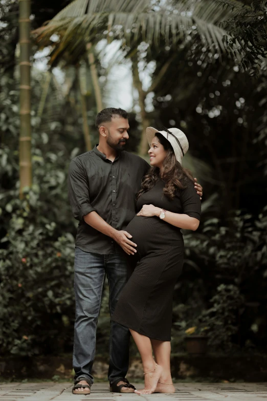 pregnant couple looking into each others eyes in a forest