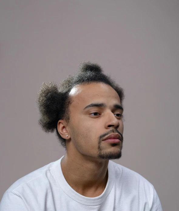 man with shaved hair, white shirt, and light gray background