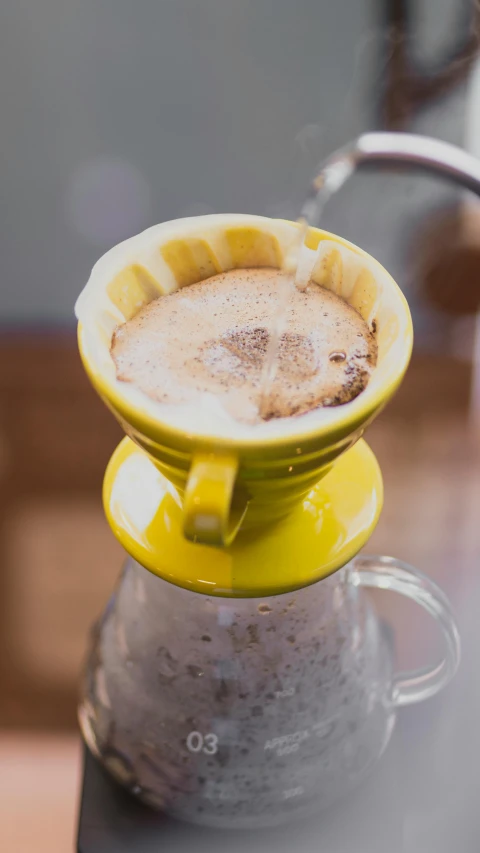 a yellow cup with an upside down cap in front of a faucet