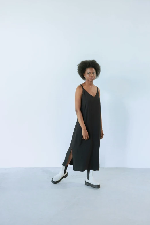 a woman posing for the camera wearing a black dress and platform shoes