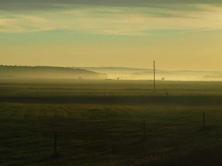 the mist is hanging off of a grassy field