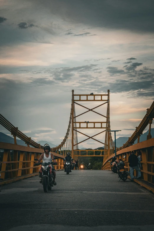 a group of motorcycles ride over a bridge