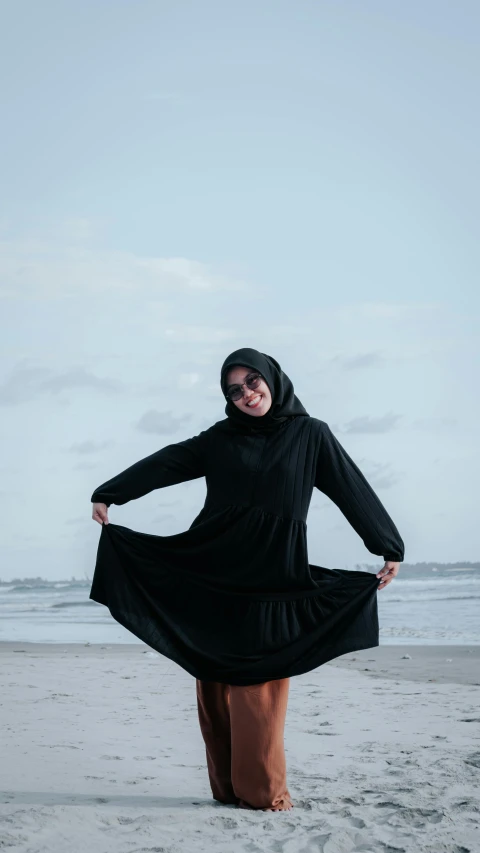 young woman in black hijab standing on beach