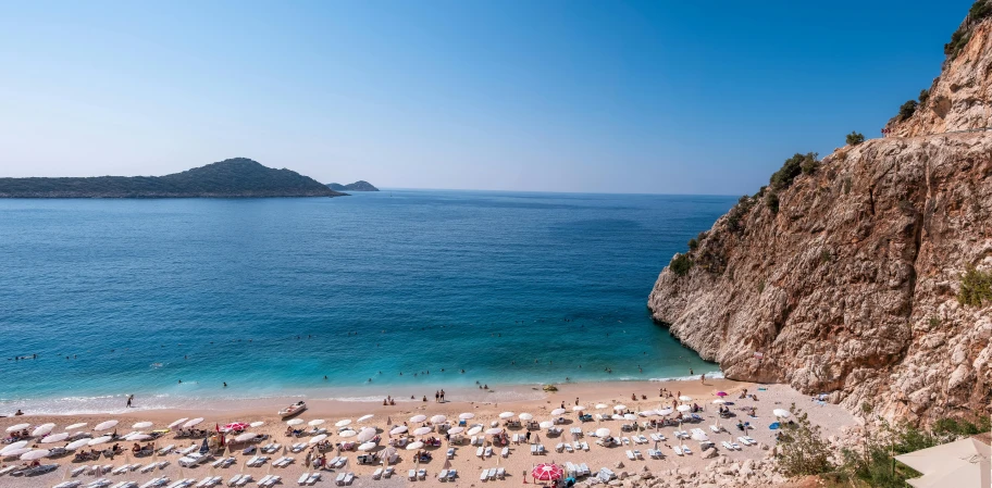 people on the beach, overlooking an island and blue ocean