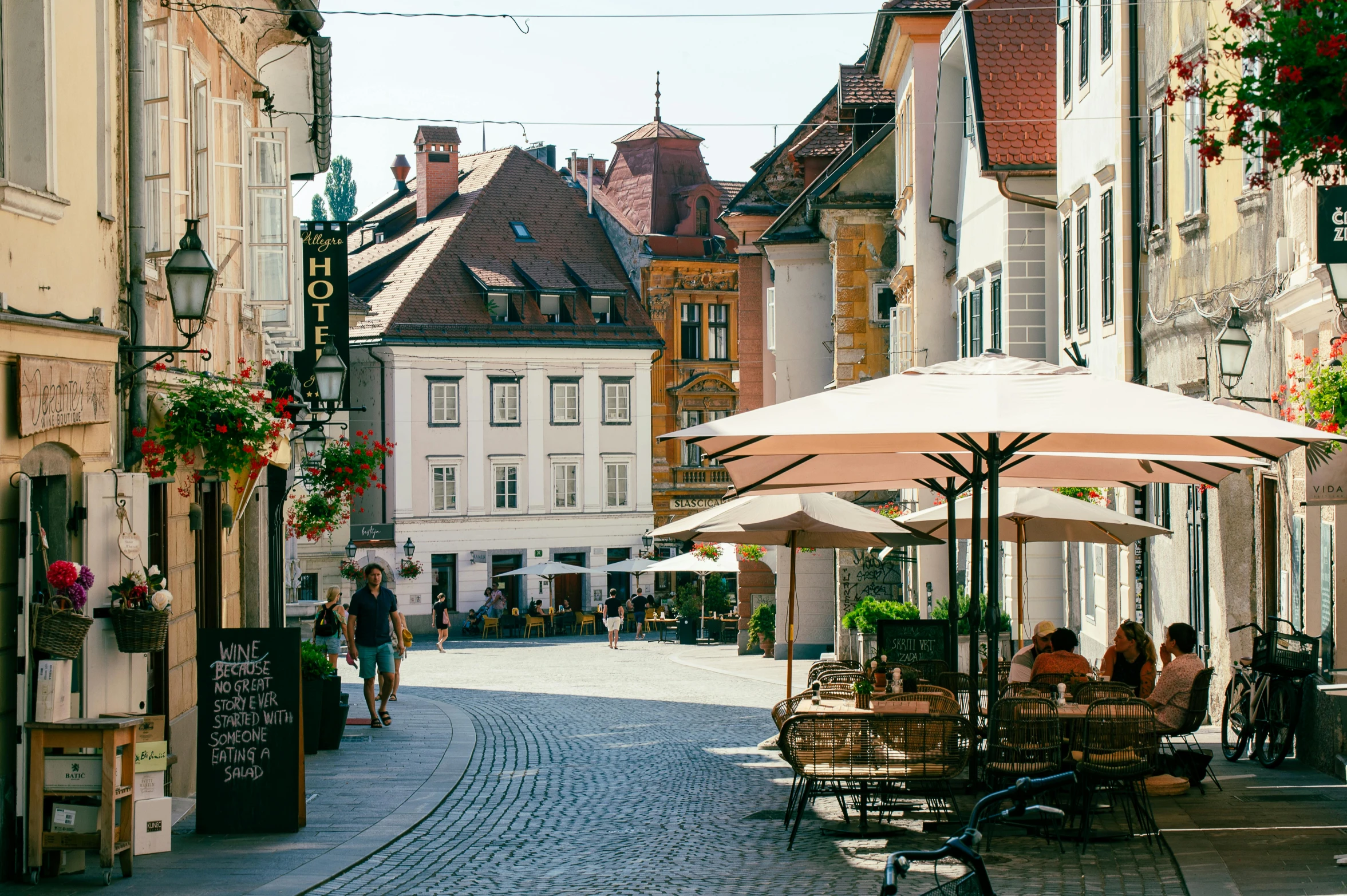 people sitting at tables on an old fashioned cobble stone walkway