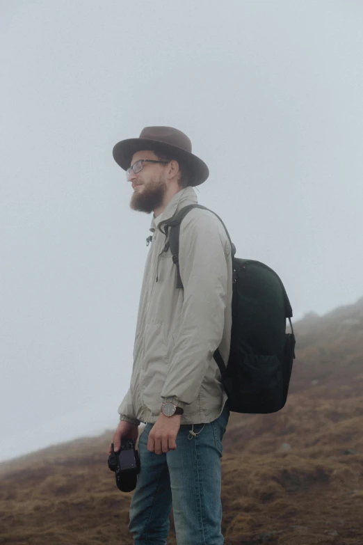 a man in glasses wearing a hat and holding a camera