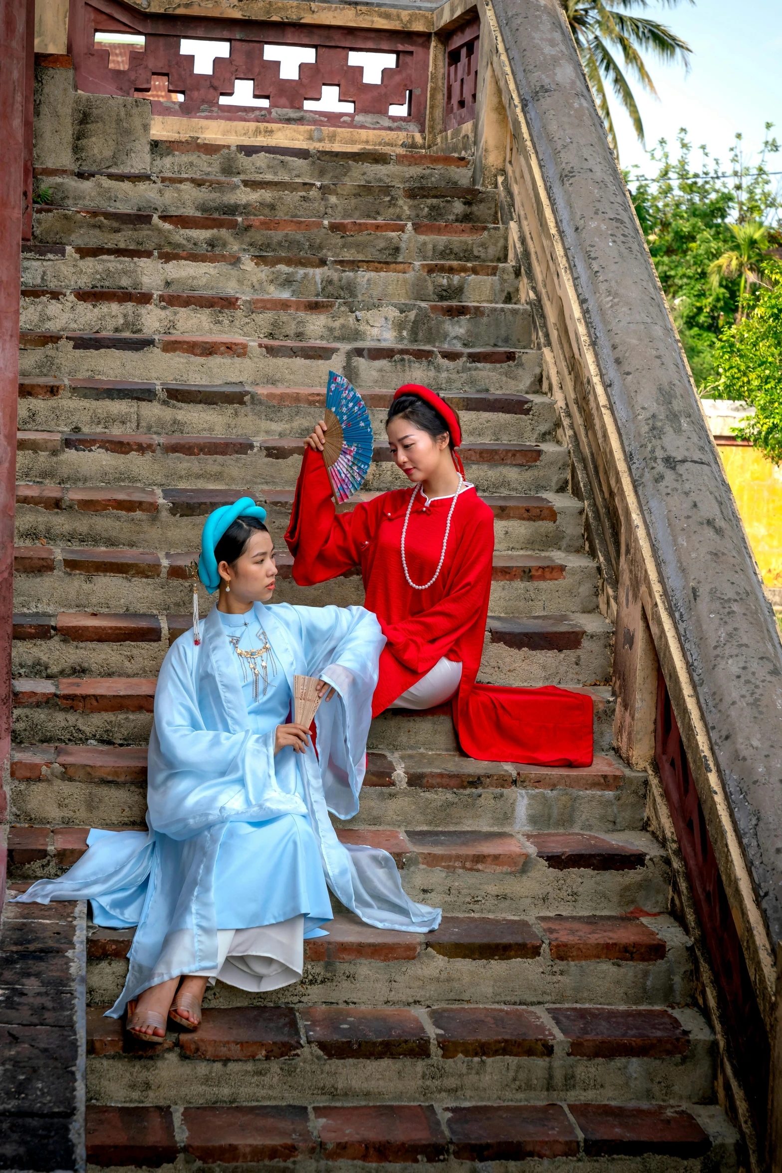 two women dressed in oriental costume sitting down on stairs