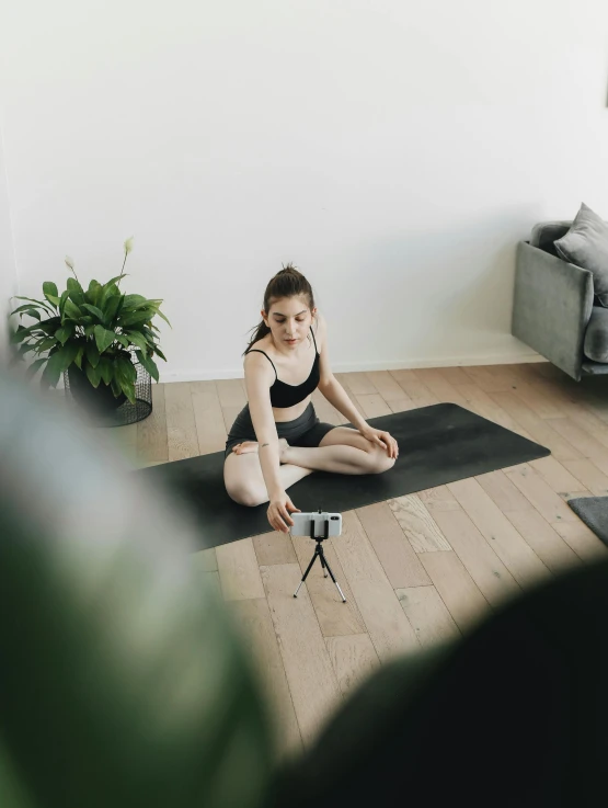 woman in black yoga top sitting on a yoga mat