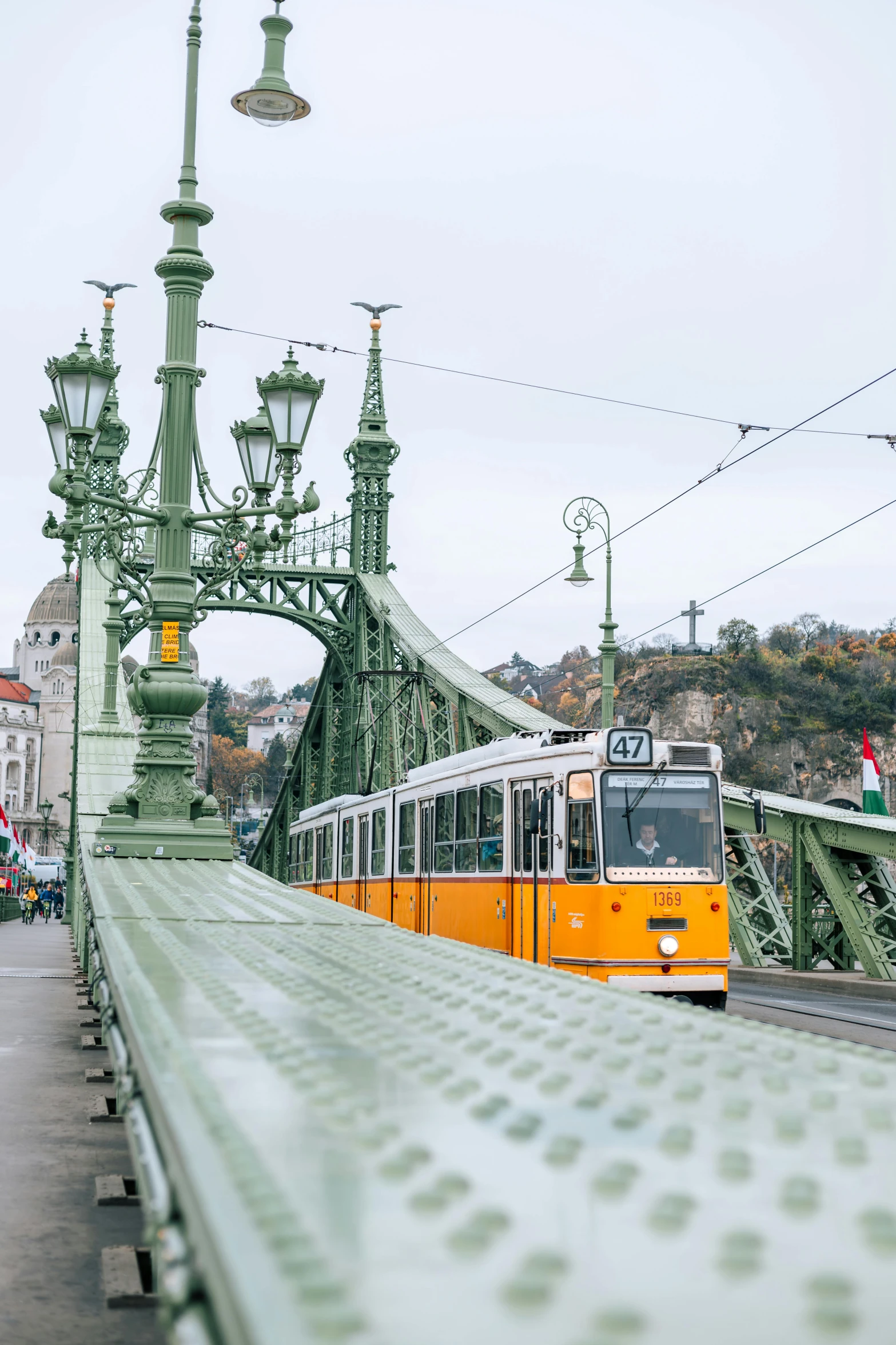 a yellow train travels on the tracks under an iron bridge